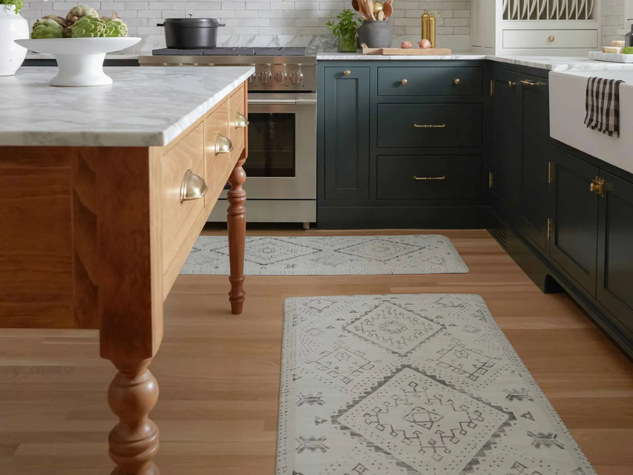 A rustic kitchen featuring a patterned rug that matches the wooden island and dark cabinetry.