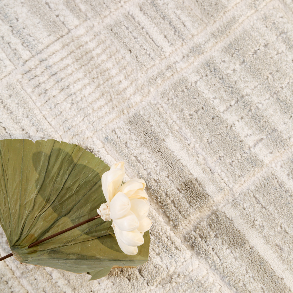 Textured neutral geometric rug with flower and leaf accent, perfect for modern decor.