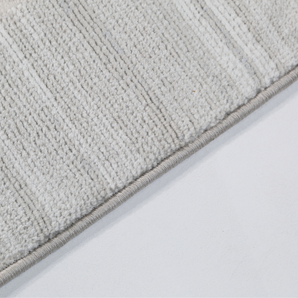 Textured light gray woven rug edge in modern home decor.