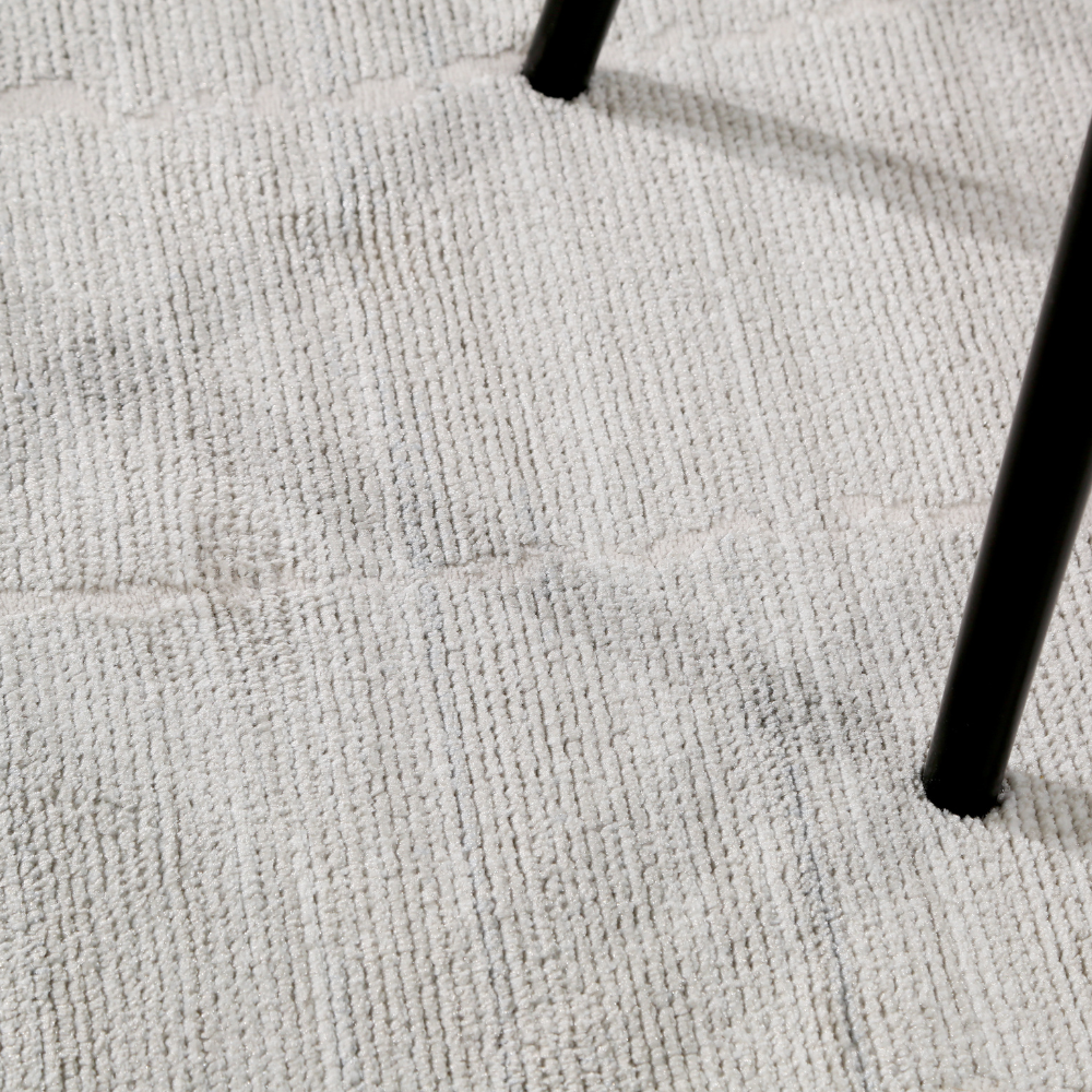 Textured light gray woven rug under a black chair in a stylish living space.