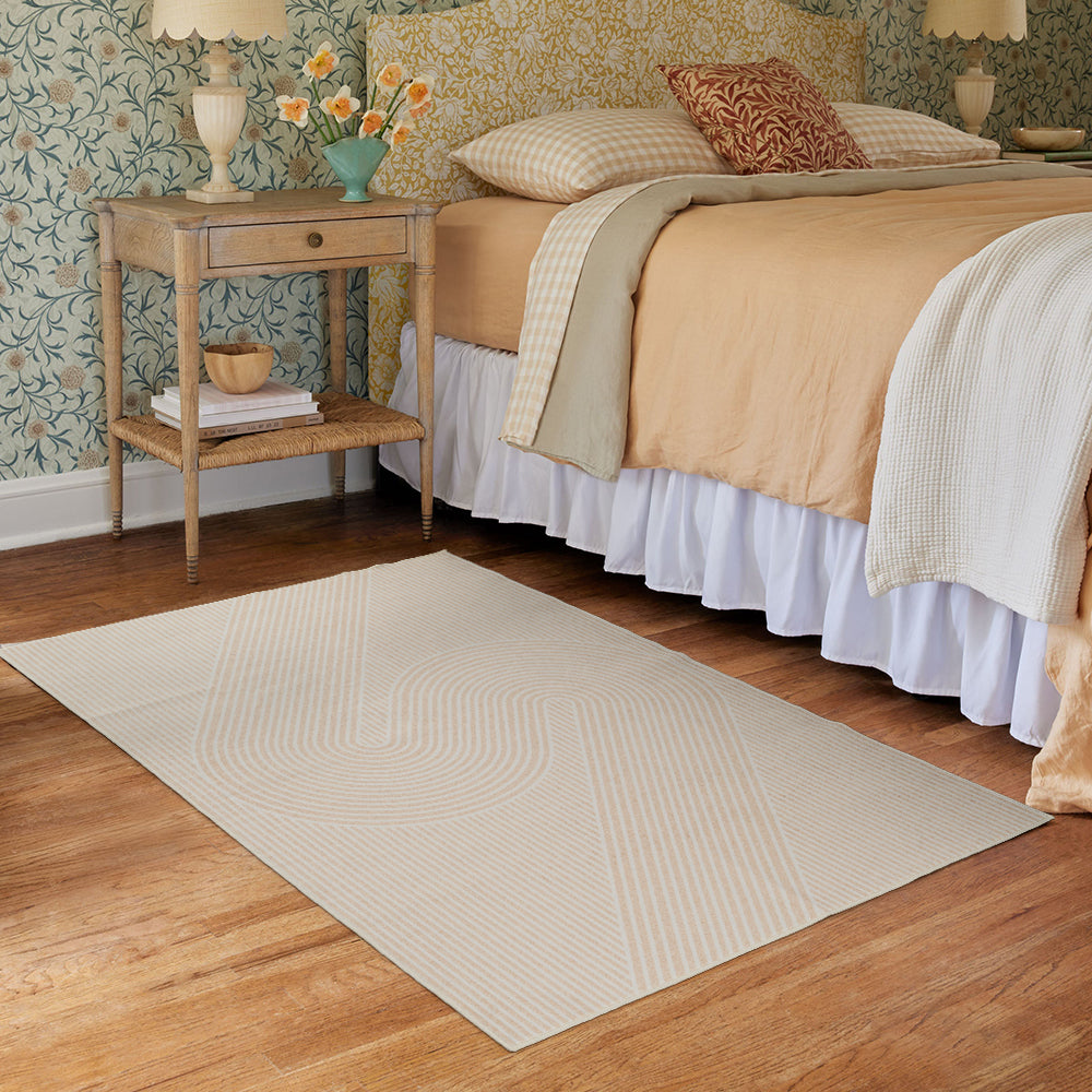 Serpentine Whisper rug in light tones on wooden floor beside a bed