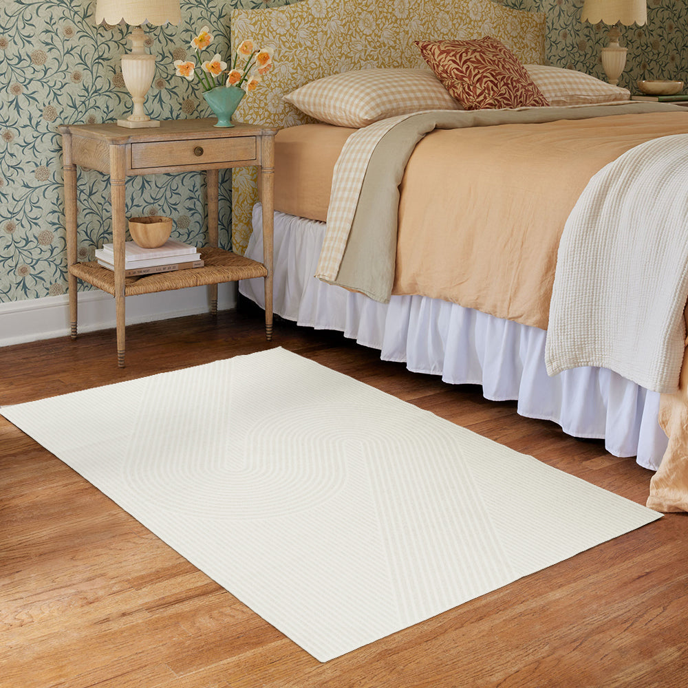 Serpentine Whisper modern rug with curved lines beside a bed in a cozy bedroom